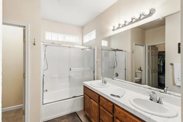 a bathroom with a granite countertop sink mirror shower and double
