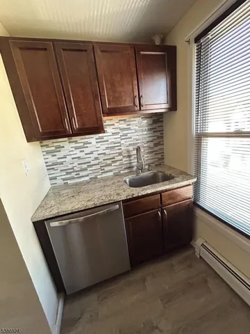 a kitchen with granite countertop stainless steel appliances wooden cabinets a sink and a window