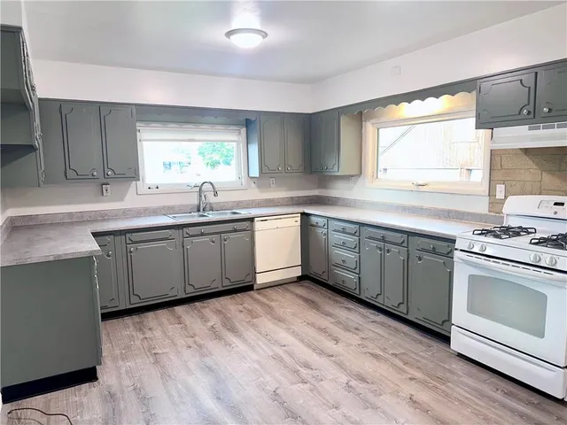 a kitchen with stainless steel appliances granite countertop a sink cabinets and wooden floors