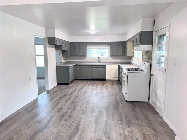 a kitchen with a hard wood floor a sink dishwasher stove and refrigerator with wooden floor