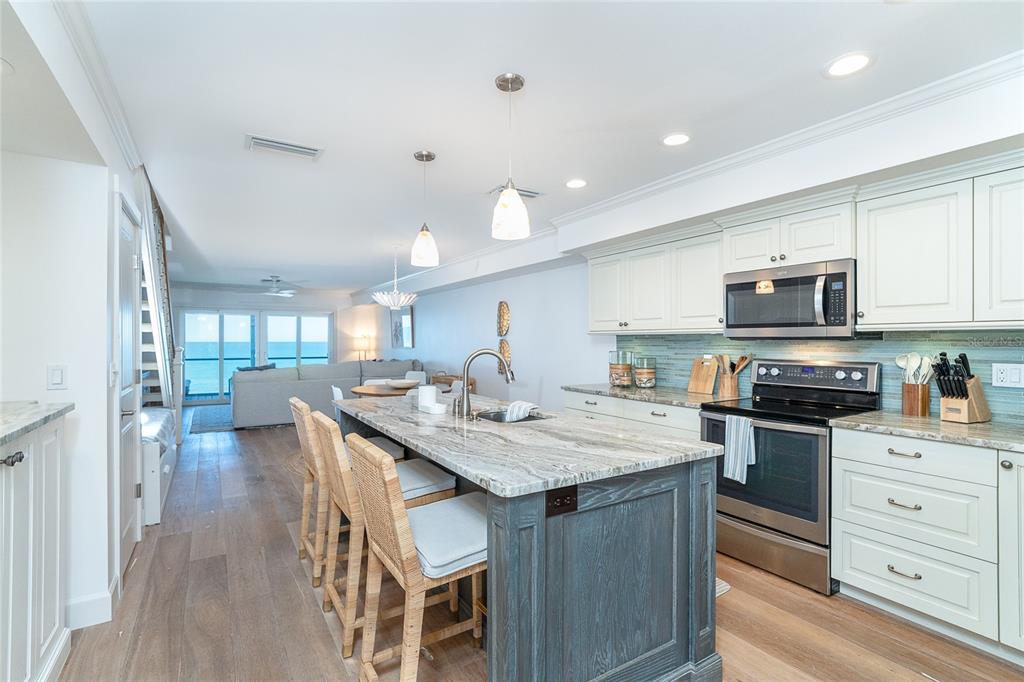 301 South Gulf Boulevard, Unit 25 Placida, FL 33946 - Photo 8 of 68 a kitchen with stainless steel appliances kitchen island granite countertop a stove top oven a sink a dining table and chairs with wooden floor