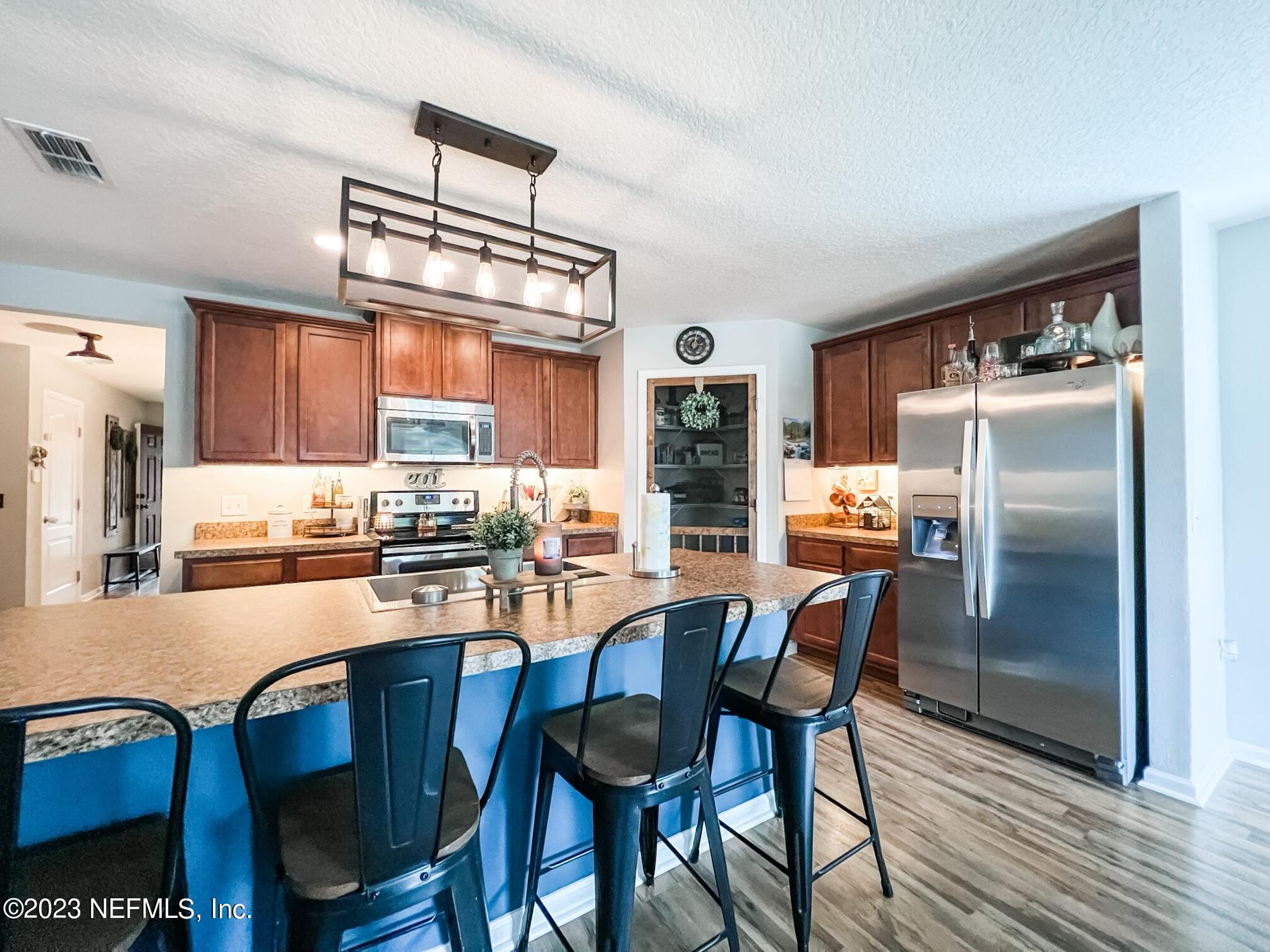 45190 Dutton Way Callahan, FL 32011 - Photo 14 of 29 a kitchen with stainless steel appliances a dining table chairs refrigerator and cabinets