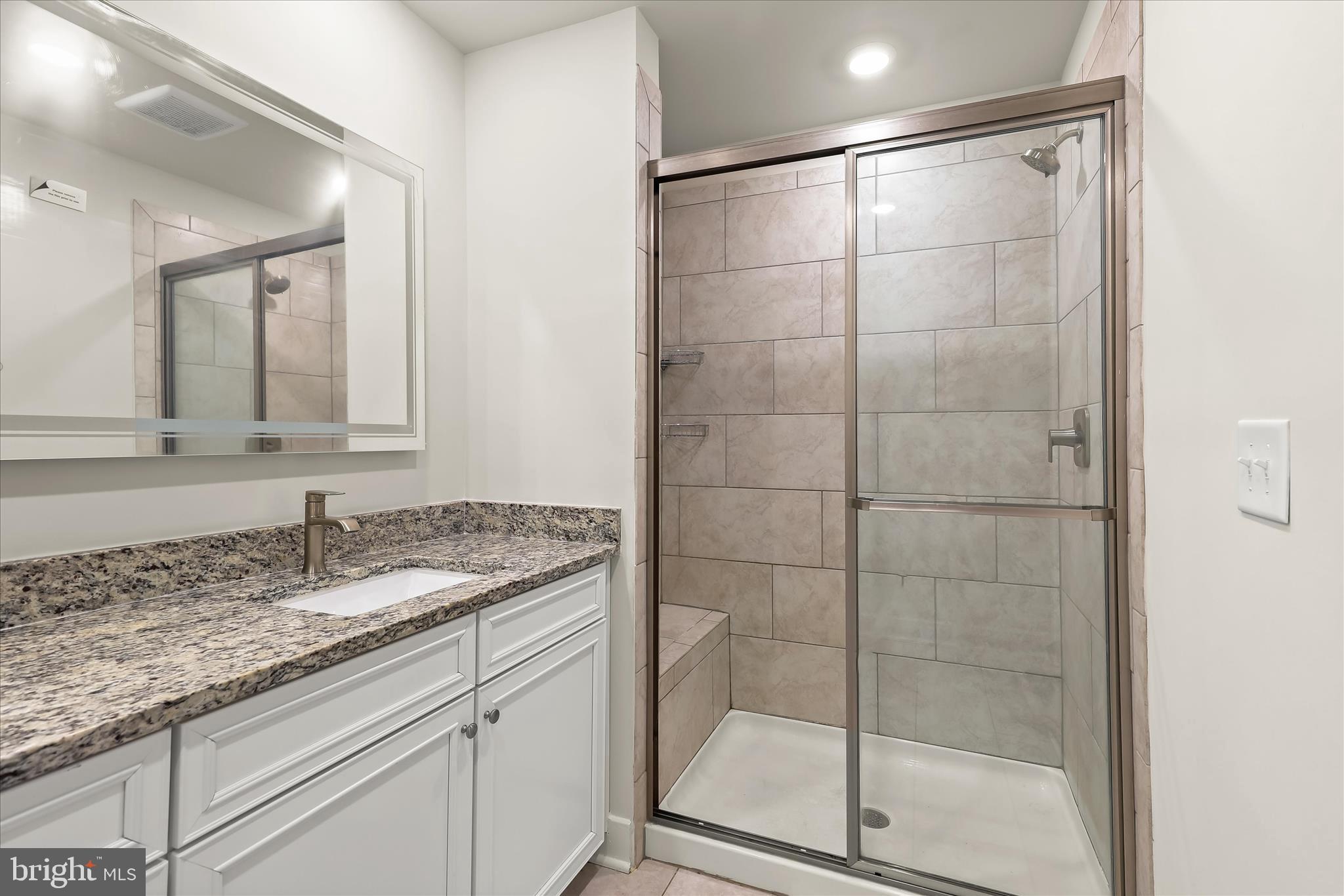 304 Sweetbay Road Essex, MD 21221 - Photo 23 of 66 a bathroom with a granite countertop sink a mirror and shower