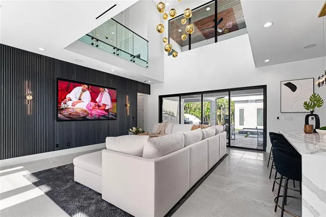 a living room with furniture a flat screen tv and a floor to ceiling window