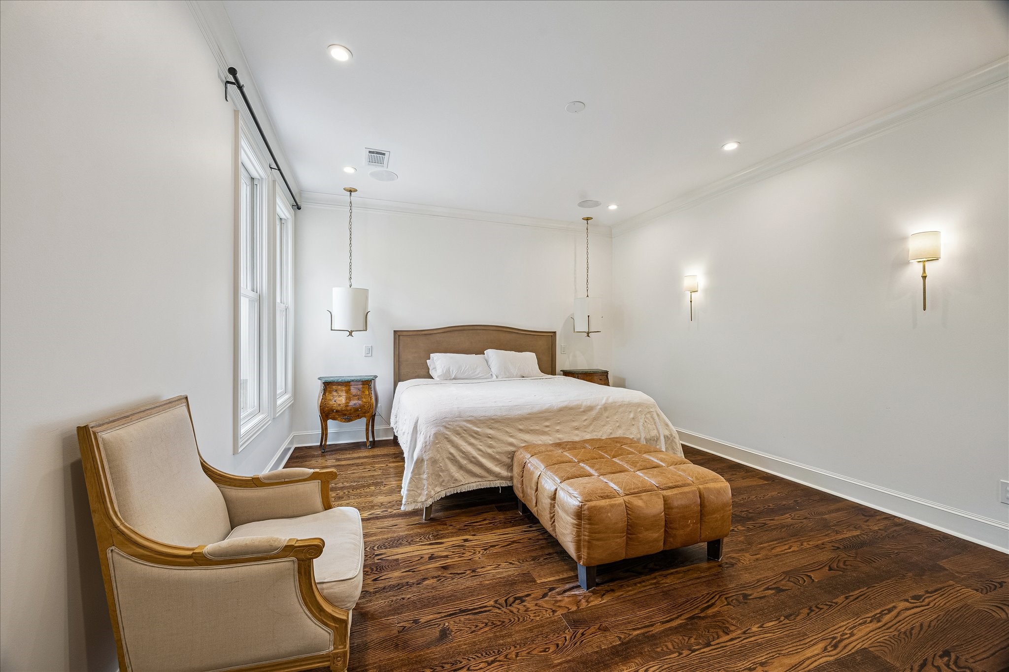 2368 Timber Lane Houston, TX 77027 - Photo 21 of 46 The stunning primary suite is a refined retreat, featuring rich hardwood floors, elevated ceilings, and integrated surround sound for a luxurious living experience. Overlooking the courtyard below, dual windows invite in soft natural light, while elegant sconces and designer suspended luminaires create a warm, sophisticated ambiance throughout the space.