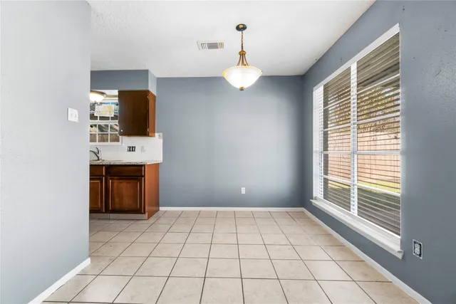 a view of an empty room with a window and kitchen view