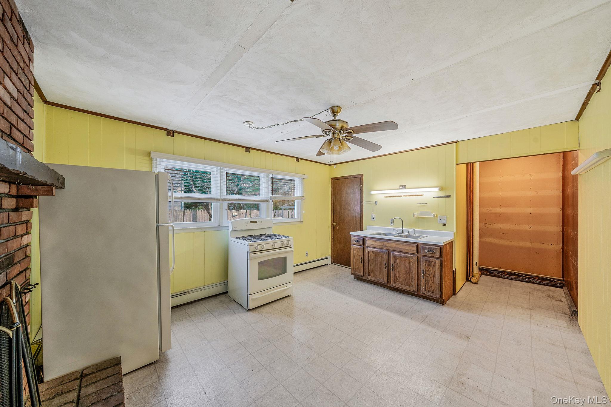 120 Rustic Road Port Jefferson, NY 11777 - Photo 23 of 45 Kitchen with light floors, gas range gas stove, freestanding refrigerator, light countertops, and a baseboard heating unit