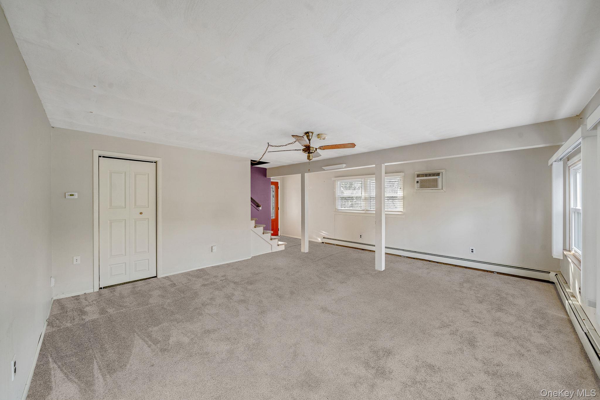 120 Rustic Road Port Jefferson, NY 11777 - Photo 24 of 45 Unfurnished living room with a ceiling fan, carpet floors, a baseboard radiator, stairs, and a wall mounted air conditioner