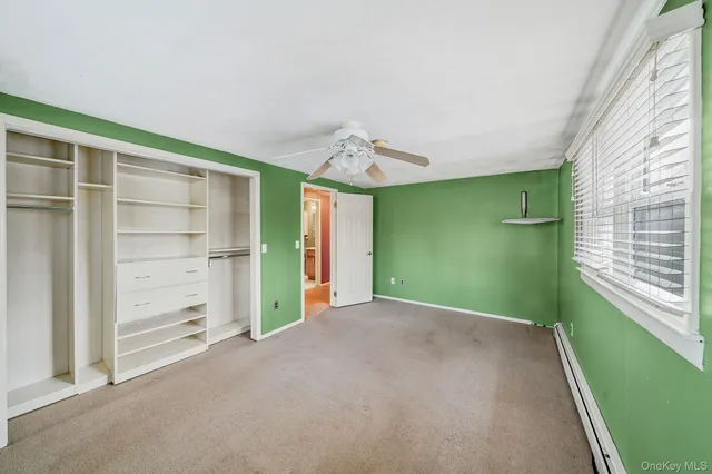 a view of an empty room with a window and a kitchen