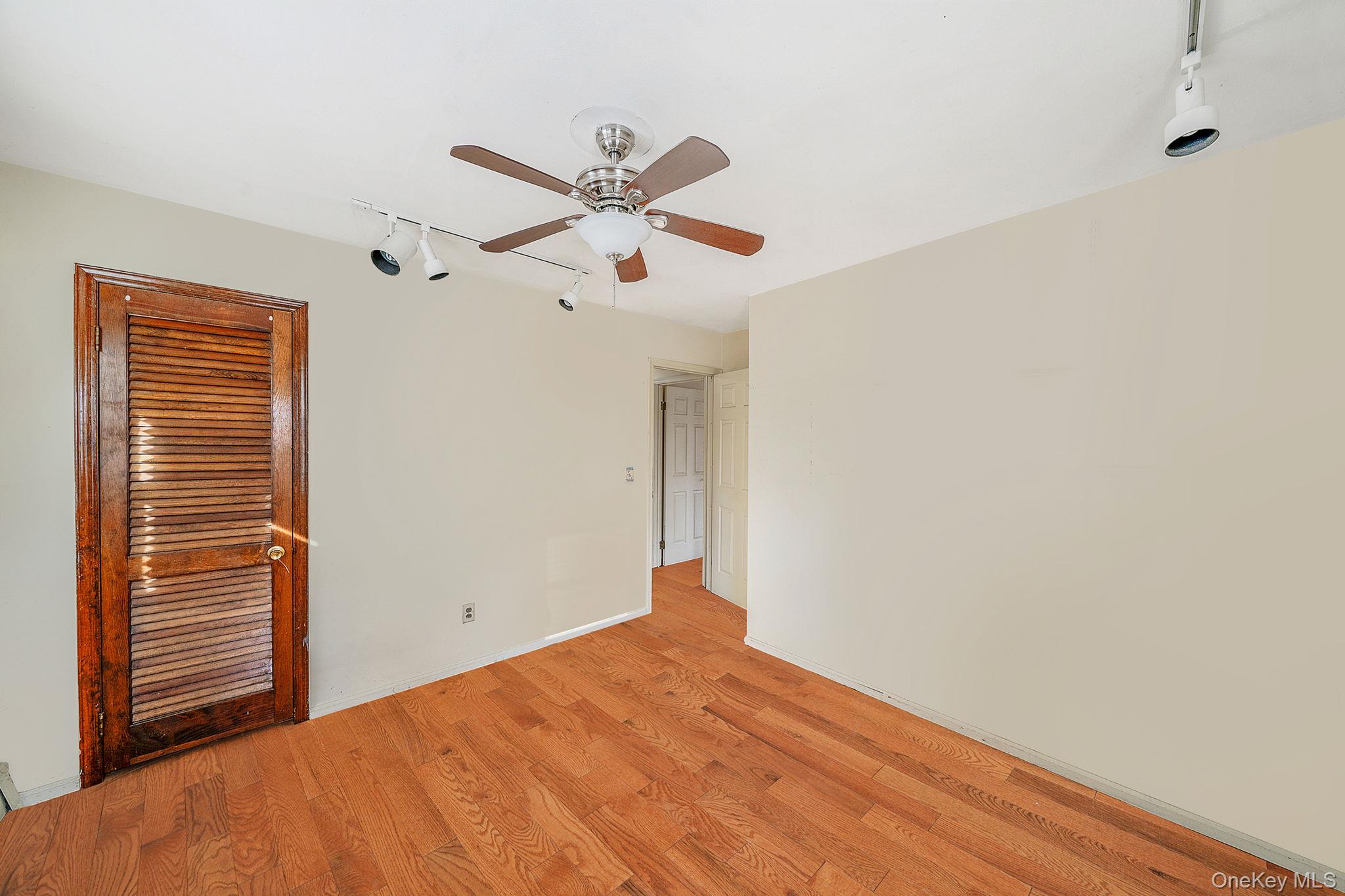 120 Rustic Road Port Jefferson, NY 11777 - Photo 37 of 45 Empty room featuring rail lighting, wood finished floors, and a ceiling fan
