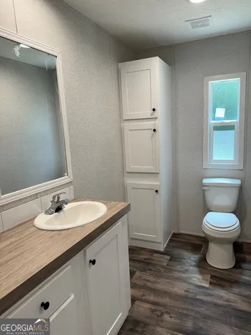 a bathroom with a granite countertop sink toilet and a mirror