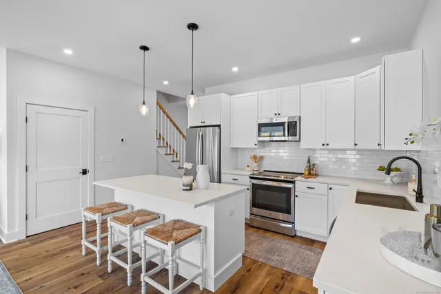 a kitchen with stainless steel appliances kitchen island granite countertop a sink a stove a dining table and chairs