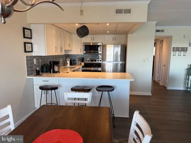 a kitchen with stainless steel appliances kitchen island granite countertop a table chairs and a refrigerator