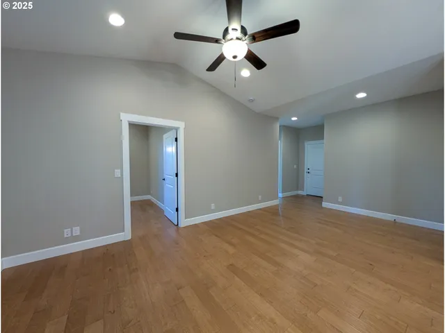 an empty room with chandelier fan and windows