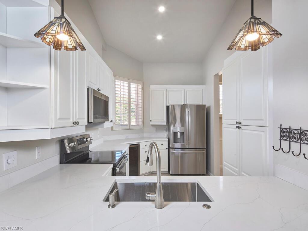1033 Egrets Walk Circle, Unit 203 Naples, FL 34108 - Photo 19 of 35 a kitchen with stainless steel appliances granite countertop a refrigerator a microwave a stove and white cabinets