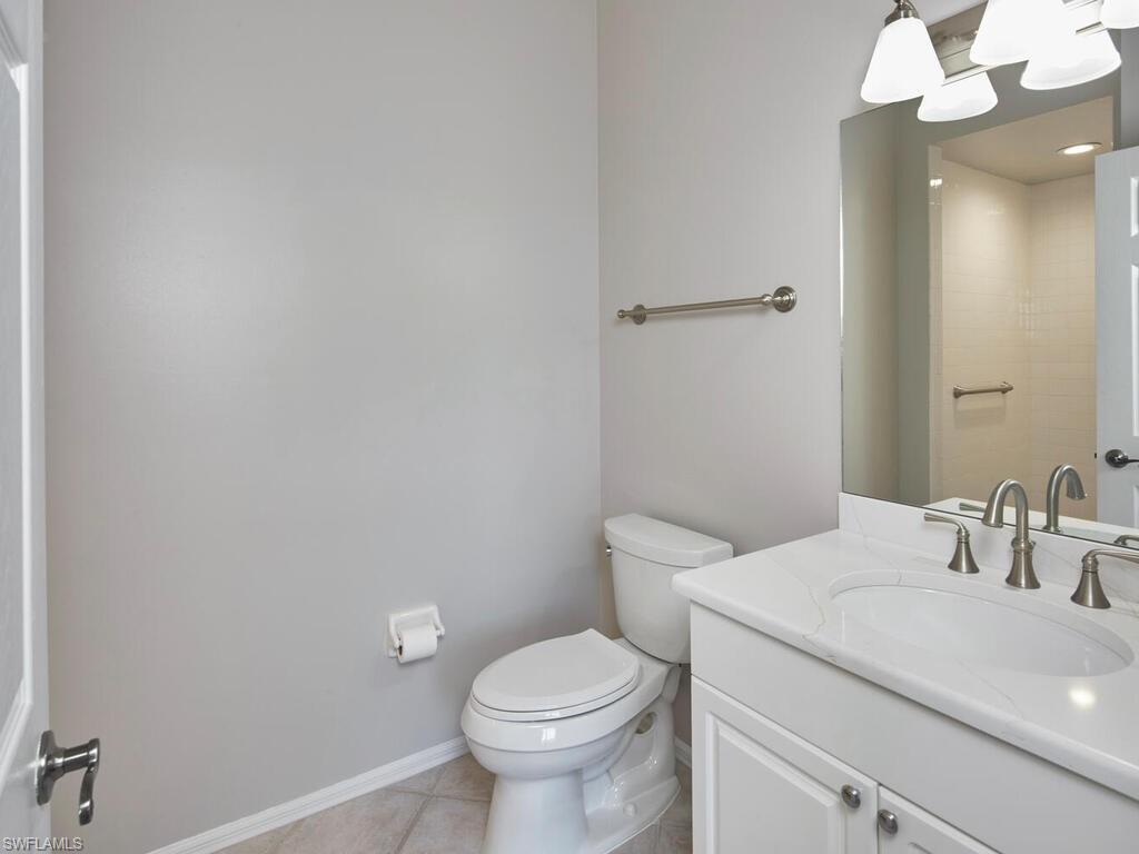 1033 Egrets Walk Circle, Unit 203 Naples, FL 34108 - Photo 22 of 35 a bathroom with a sink a toilet and a mirror