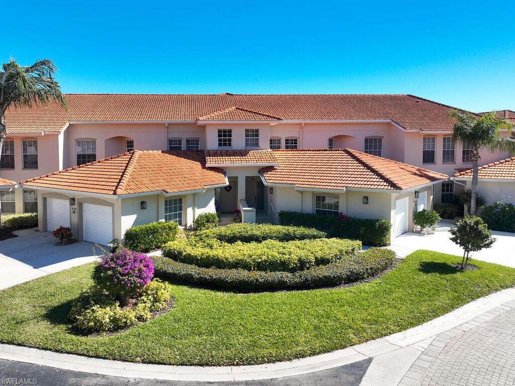 1033 Egrets Walk Circle, Unit 203 Naples, FL 34108 - Photo 27 of 35 a front view of a house with a yard