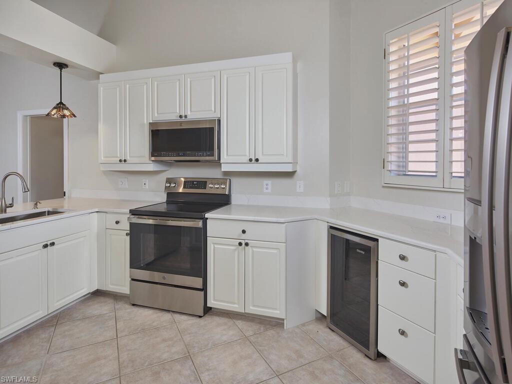 1033 Egrets Walk Circle, Unit 203 Naples, FL 34108 - Photo 4 of 35 a kitchen with white cabinets and white appliances