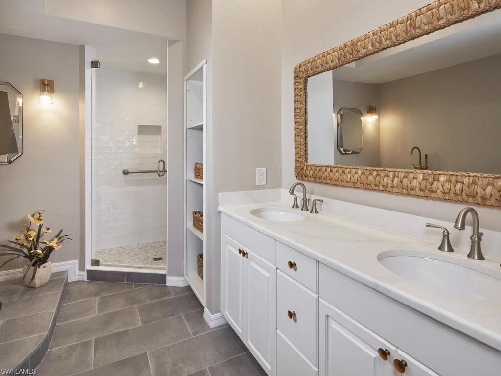 1033 Egrets Walk Circle, Unit 203 Naples, FL 34108 - Photo 6 of 35 a bathroom with a double vanity sink and a mirror