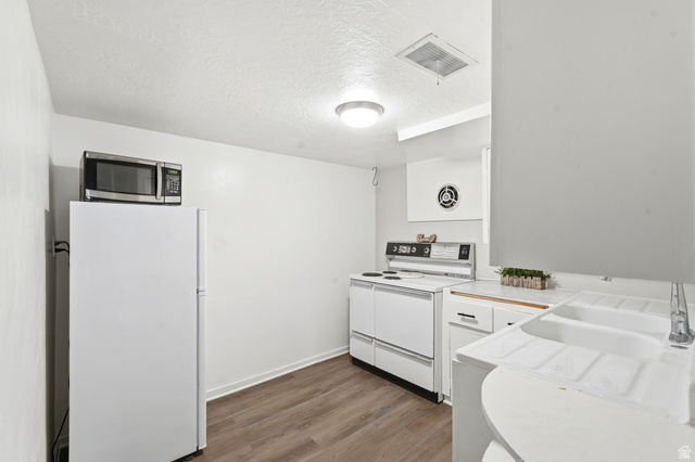 270 East 700 North Logan, UT 84321 - Photo 21 of 42 Kitchen space featuring wood-finish flooring, white cabinetry, a white refrigerator, and a white range