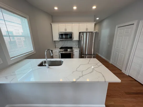 a kitchen with stainless steel appliances a sink a stove a refrigerator and cabinets