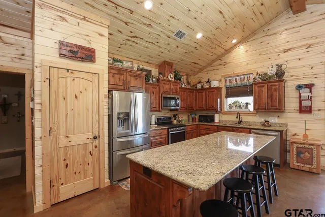 a kitchen with stainless steel appliances granite countertop a table chairs and refrigerator