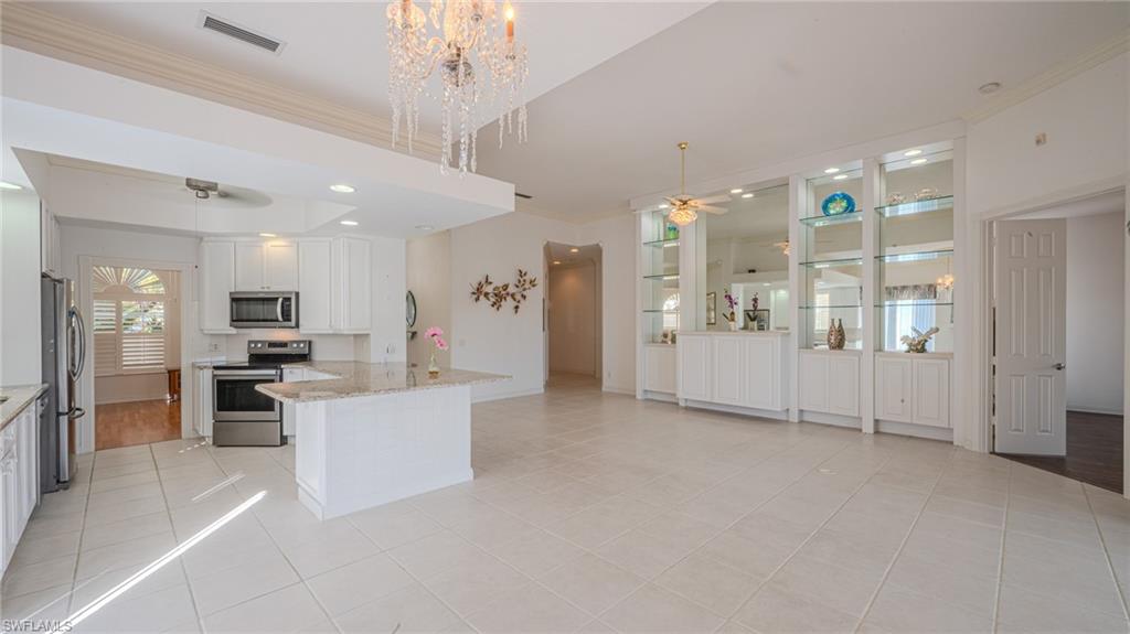 3766 Whidbey Way Naples, FL 34119 - Photo 11 of 50 Kitchen featuring white cabinets, a ceiling fan, stainless steel appliances, crown molding, and light stone countertops