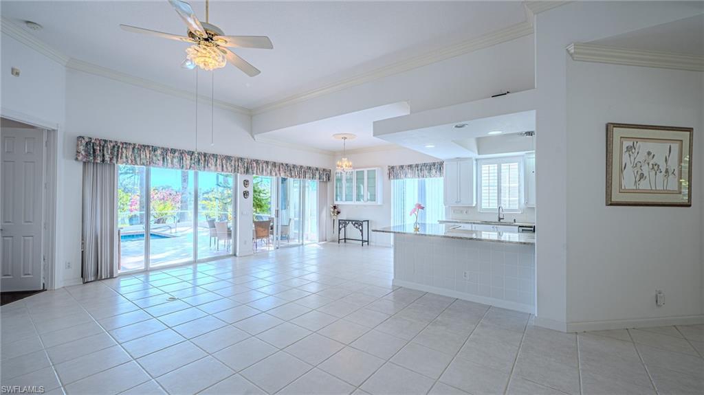 3766 Whidbey Way Naples, FL 34119 - Photo 14 of 50 Kitchen featuring white cabinetry, light stone countertops, a ceiling fan, crown molding, and appliances with stainless steel finishes