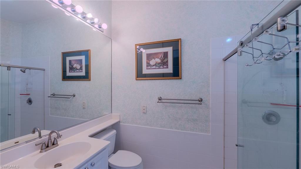 3766 Whidbey Way Naples, FL 34119 - Photo 20 of 50 Bathroom featuring vanity, wainscoting, a stall shower, and tile walls