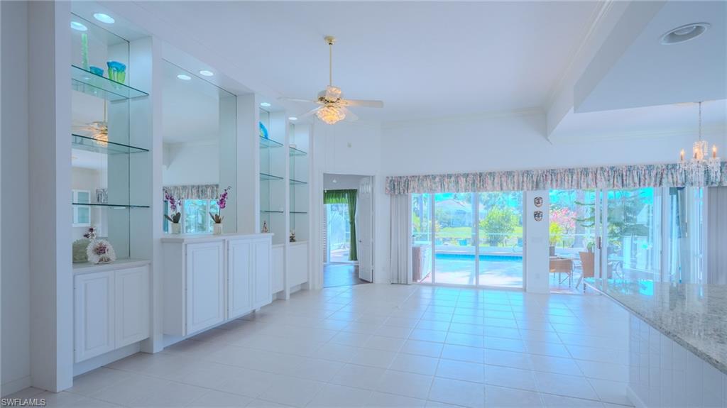3766 Whidbey Way Naples, FL 34119 - Photo 9 of 50 Empty room featuring built in shelves, ceiling fan, light tile patterned floors, and ornamental molding