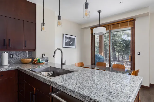 a kitchen with stainless steel appliances granite countertop a sink a stove and a wooden cabinets