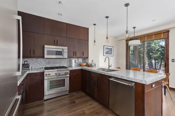 a kitchen with stainless steel appliances granite countertop a sink a stove and a wooden floor