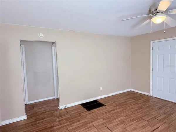 a view of empty room with wooden floor and fan