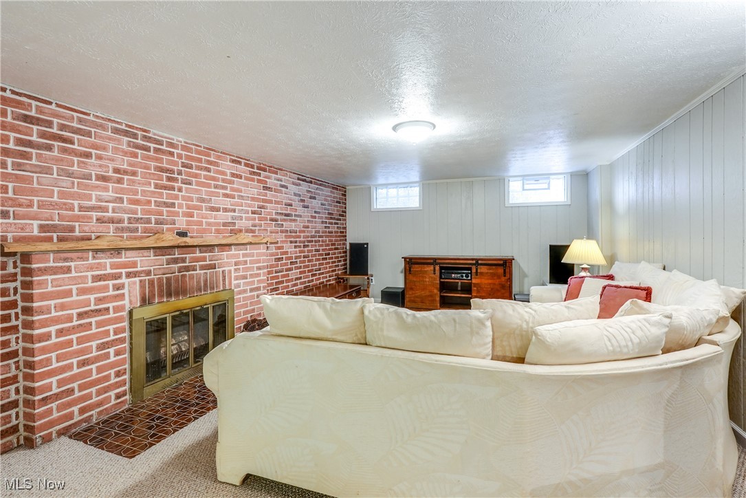 2488 Holgate Road Akron, OH 44313 - Photo 37 of 50 Recreation room with a woodburning fireplace, carpet, textured ceiling, glass block window, professionally waterproofed in 2018 with transferrable (cost $150) warranty.