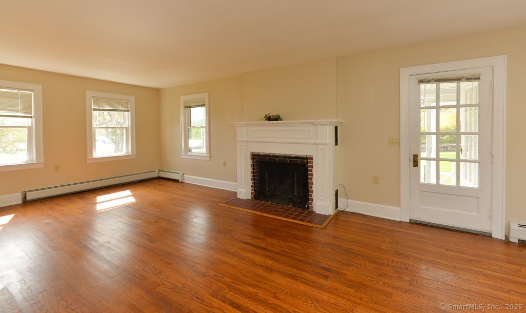 124 Purchase Brook Road Southbury, CT 06488 - Photo 5 of 26 an empty room with wooden floor fireplace and windows