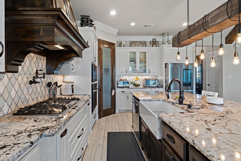 3032 Perkins Weatherford, TX 76088 - Photo 19 of 40 a kitchen with stainless steel appliances granite countertop a lot of counter space and wooden floors
