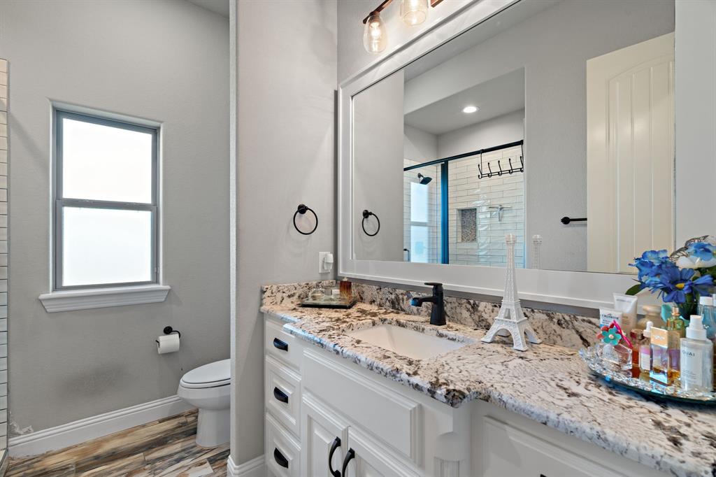 3032 Perkins Weatherford, TX 76088 - Photo 34 of 40 a bathroom with a granite countertop sink a toilet and a shower