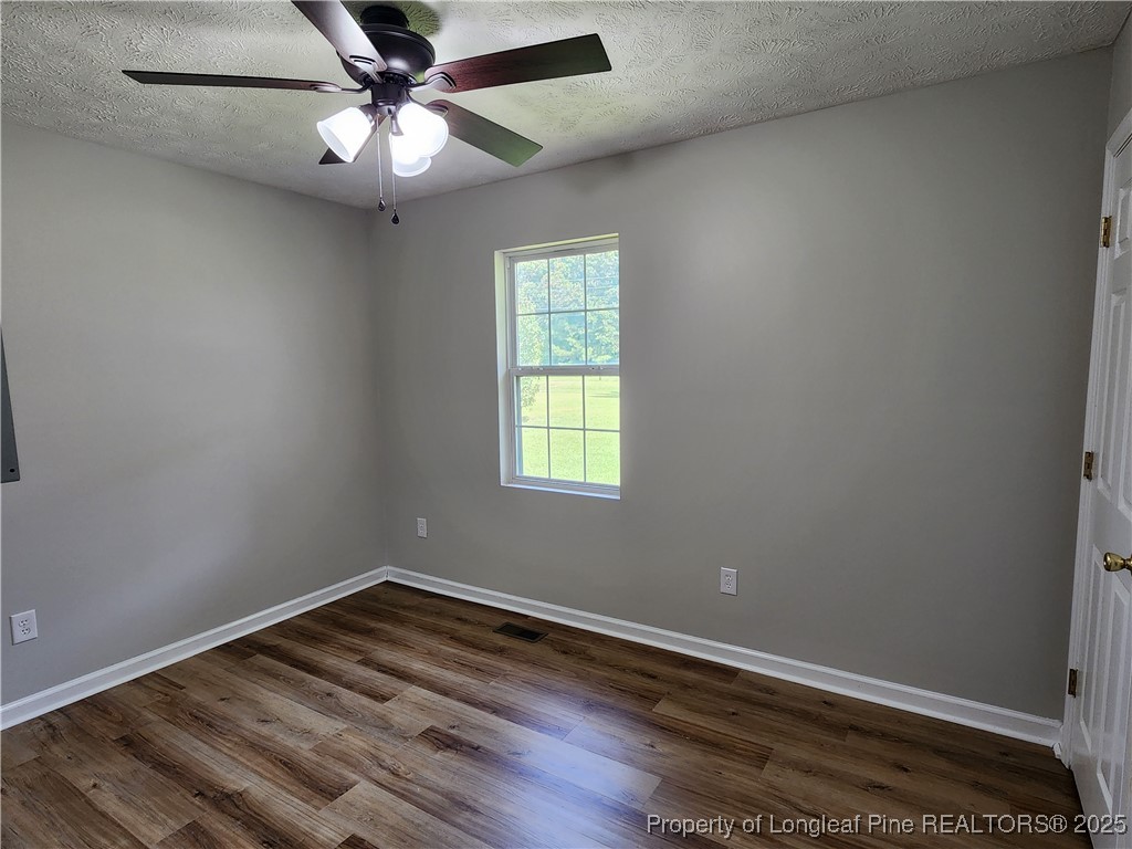 5444 Rockfish Road Raeford, NC 28376 - Photo 20 of 37 an empty room with wooden floor fan and windows