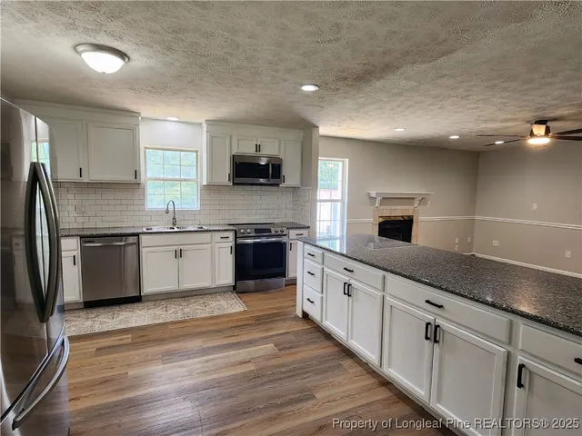 a large kitchen with stainless steel appliances kitchen island granite countertop a sink counter space and cabinets