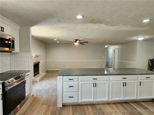 a kitchen with granite countertop a stove a sink and a microwave