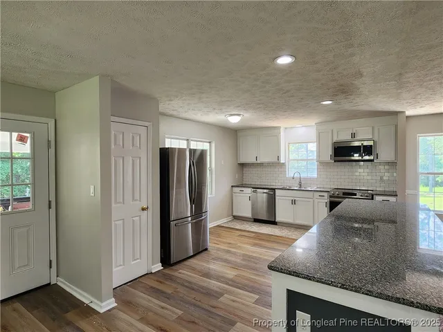 a kitchen with stainless steel appliances granite countertop a refrigerator and a stove top oven