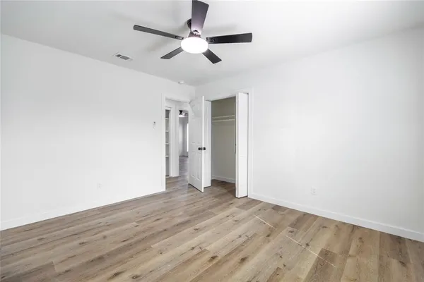 an empty room with wooden floor and a ceiling fan