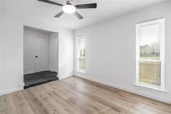 a view of an empty room with window and wooden floor