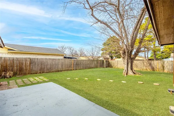 a backyard of a house with lots of green space and wooden fence