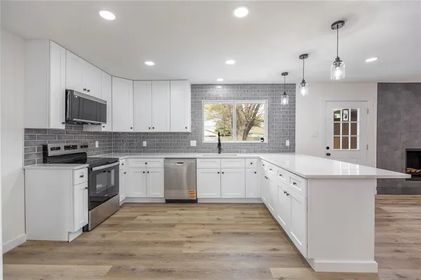 a large kitchen with granite countertop a stove top oven a sink a window and white cabinets