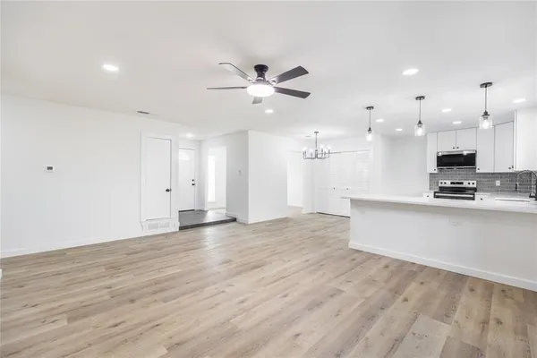 a view of kitchen with kitchen island a sink wooden floor and a stove