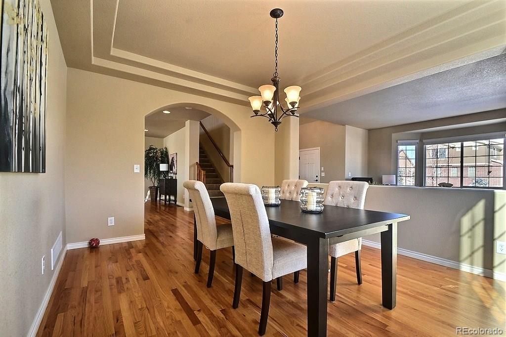 17874 West 77th Lane Arvada, CO 80007 - Photo 11 of 33 a dining room with furniture a chandelier and wooden floor