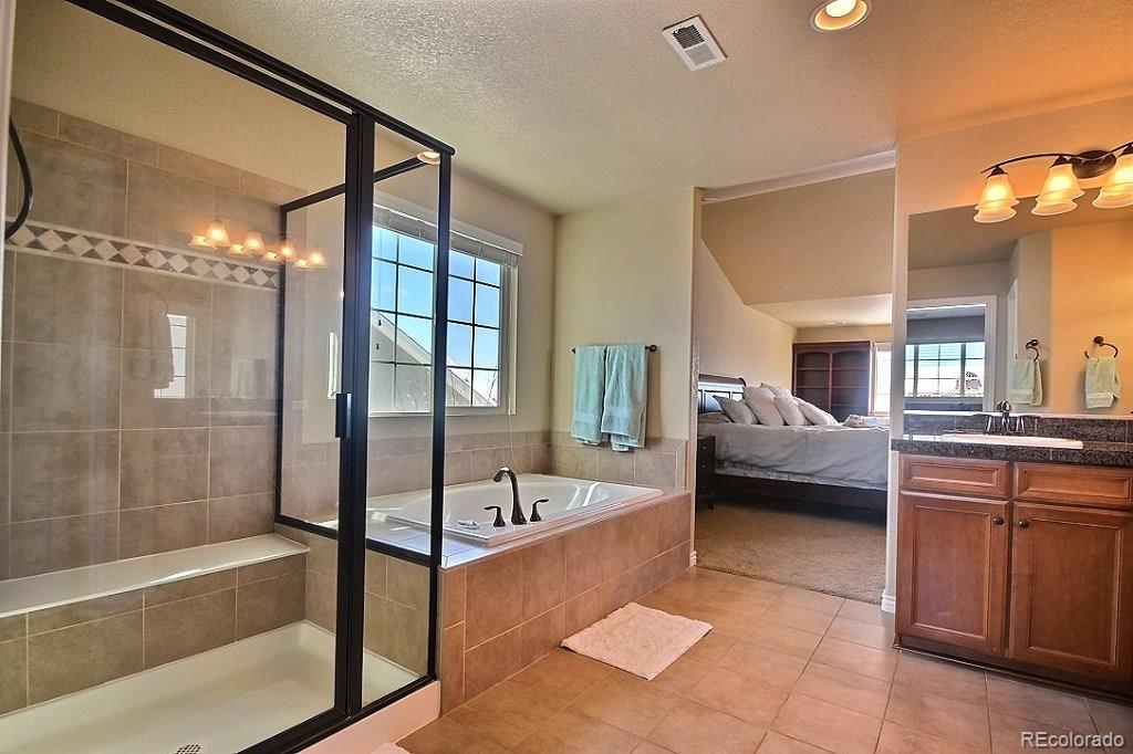 17874 West 77th Lane Arvada, CO 80007 - Photo 23 of 33 a bathroom with a tub sink shower and mirror