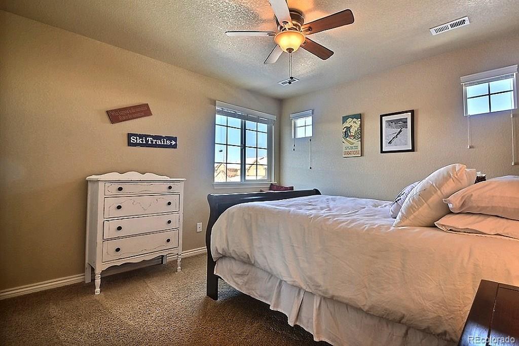 17874 West 77th Lane Arvada, CO 80007 - Photo 25 of 33 a bedroom with a bed and a chandelier