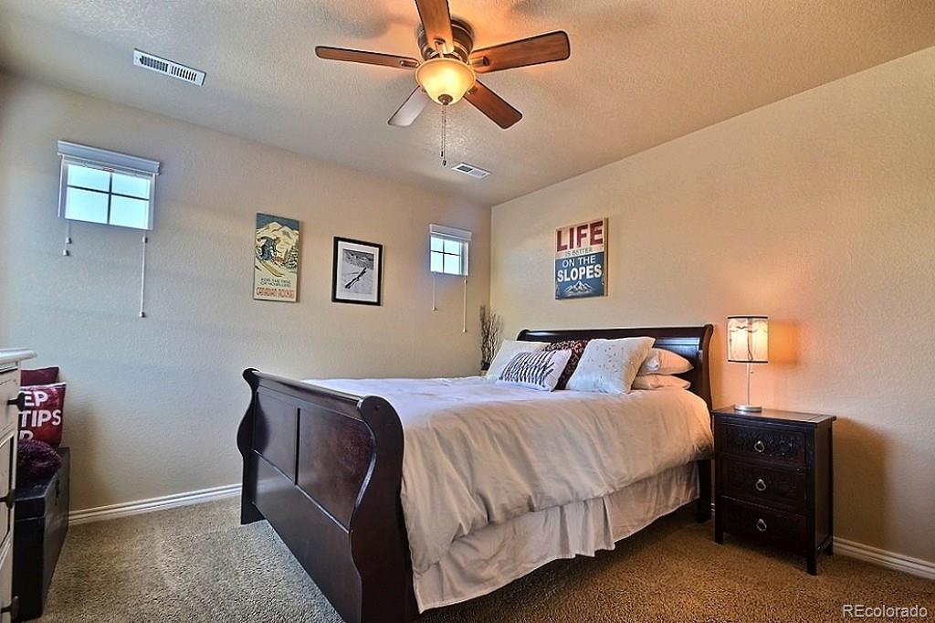 17874 West 77th Lane Arvada, CO 80007 - Photo 26 of 33 a bed room with a bed and a ceiling fan